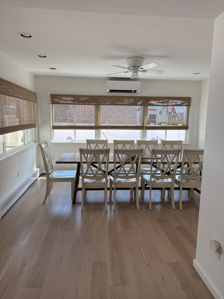 Dining area with long wood table and white chairs by the windows