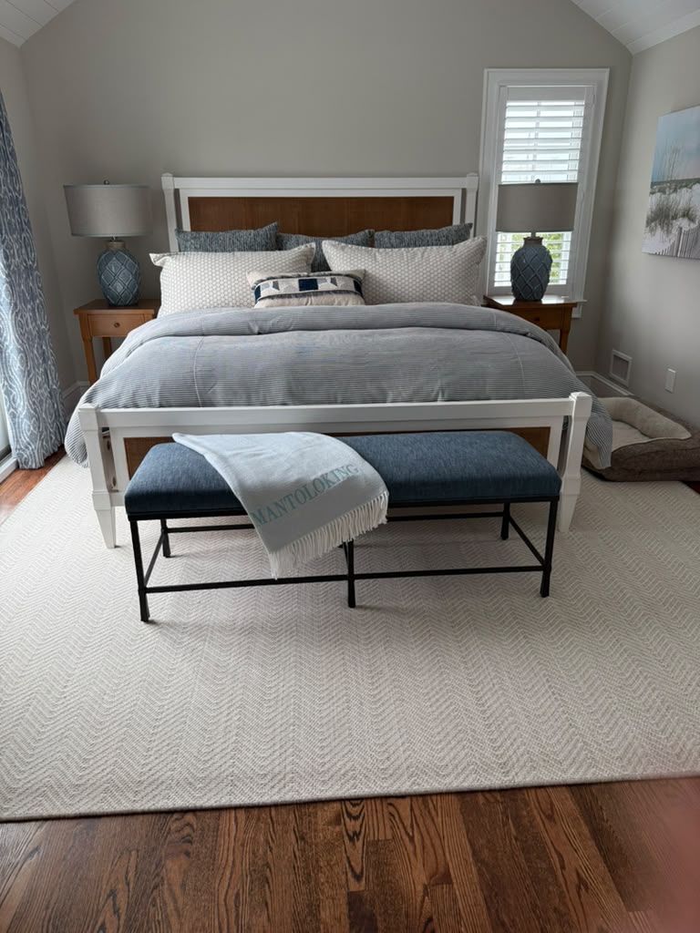 Coastal bedroom with striped bedding and upholstered bench