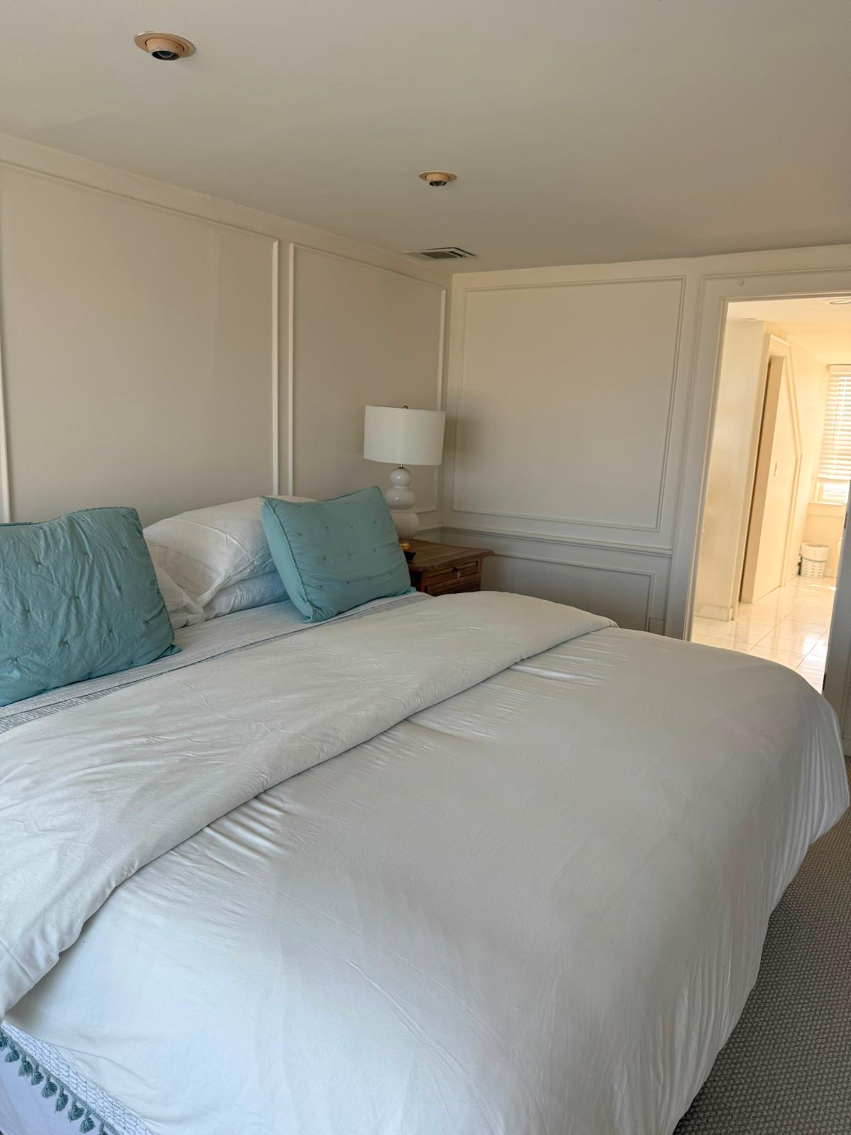 Guest bed with white bedding and turquoise accent pillows