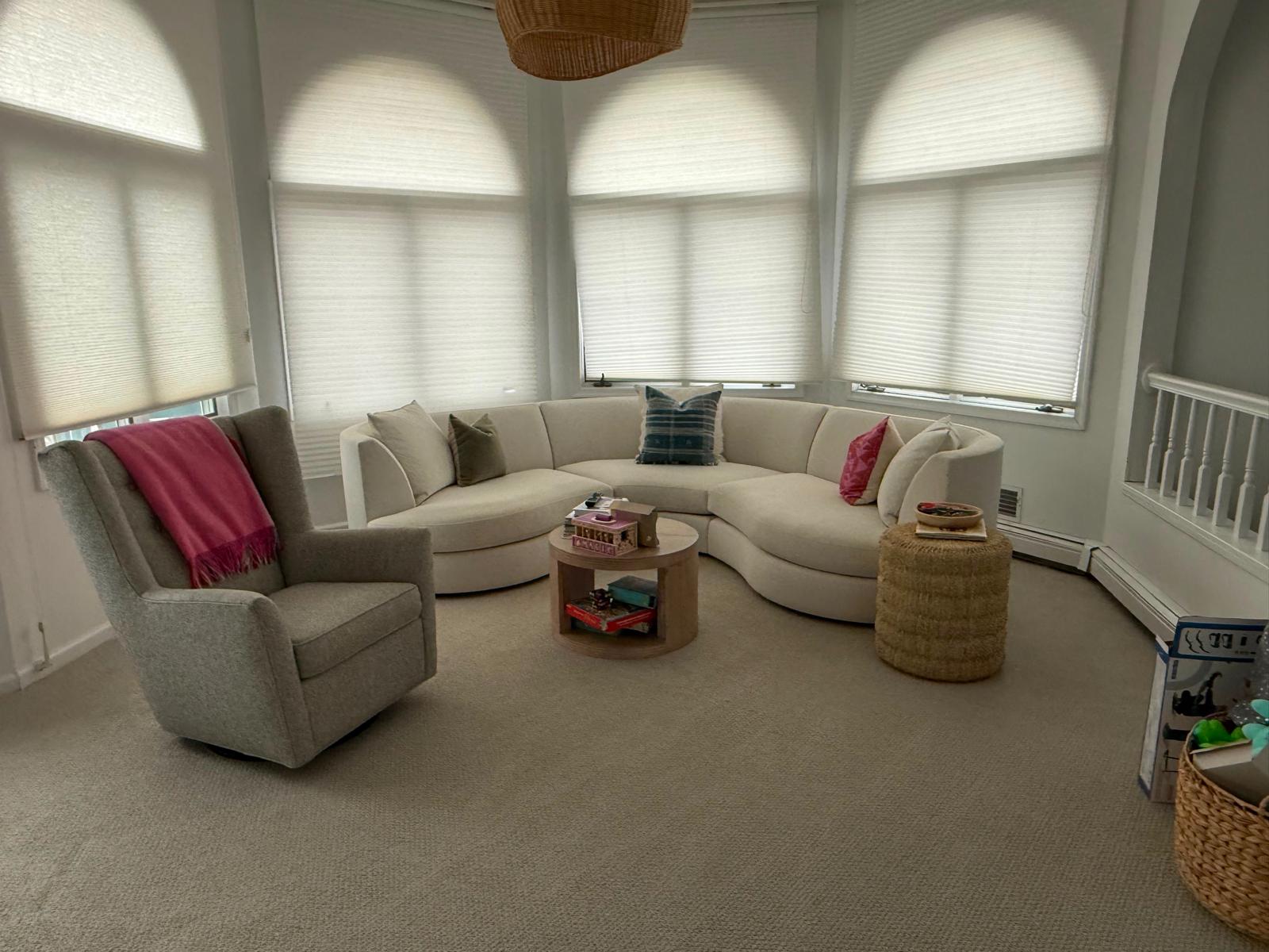 Sunlit sitting area with curved sofa and arched windows